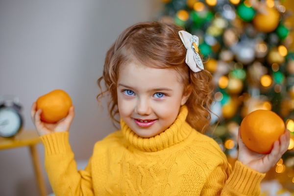 little girl playing with tangerines near the christmas tree - Готовим фруктовые шашлычки месте с детьми