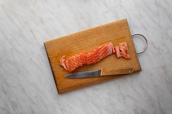 piece of salted salmon cut into slices on a kitchen board - Рыба под маринадом, постный стол