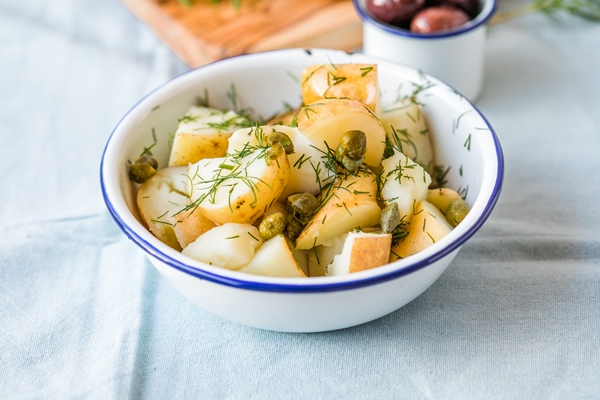 potato salad with dill and olives in a bowl on a blue background healthy food vegan and lean recipes - Простой картофельный салат