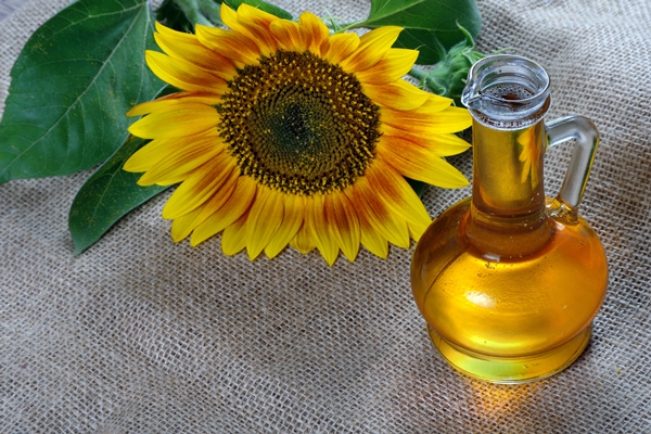 sunflower oil and a sunflower flower on the table natural vegetable oil - Салат с маринованными грибами и корейской морковью