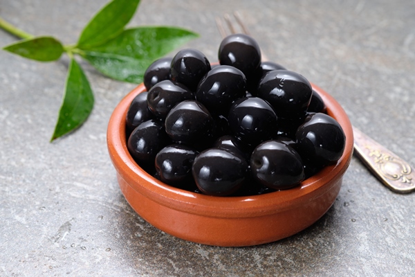 tasty black olives in the bowl on gray stone table - Салат «по-испански» с авокадо