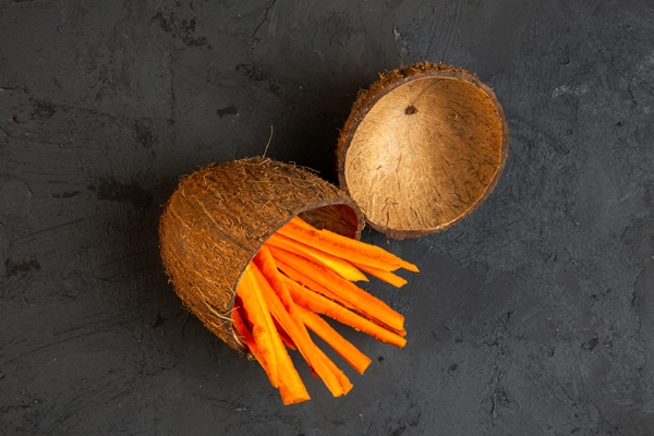 top view chopped carrots in a coconut shell on black - Слоёный салат с шампиньонами и черносливом