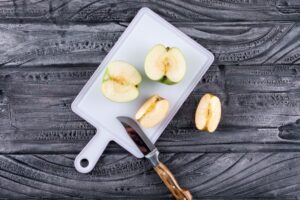 top view green apples sliced with knife on plastic board on gray wooden table and black - Замороженные яблоки на зиму