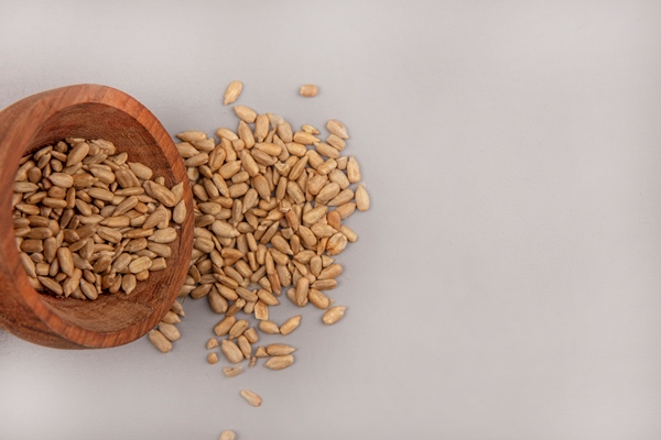 top view of organic shelled sunflower seeds falling out of a wooden bowl with copy space - Печенье на рассоле с семечками