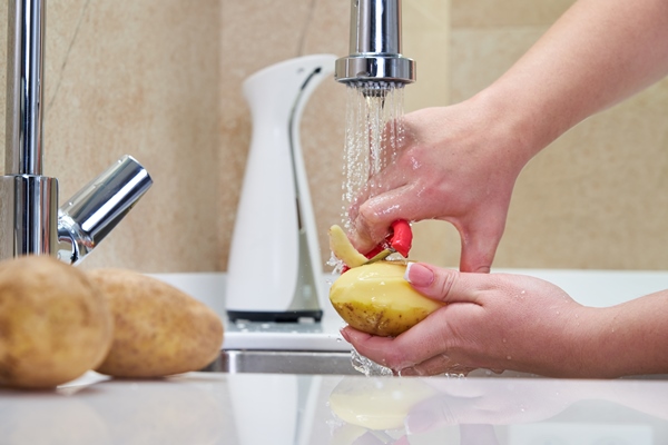 woman peeling potatoes over a sink - Зелёный суп