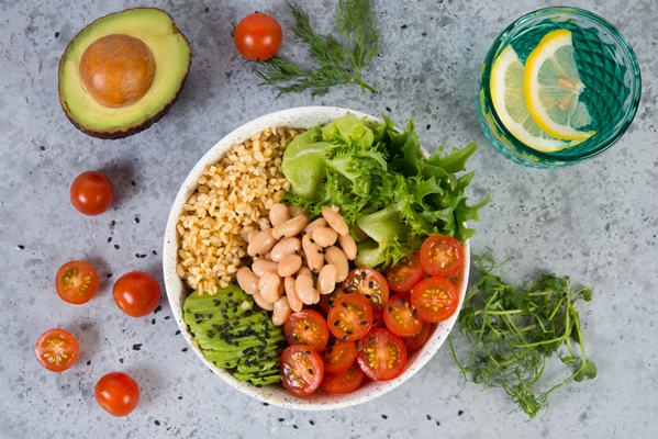a plate of fresh salad with white beans bulgur cherry tomatoes and avocado decorated with black sesame seeds with products around the plate horizontal photo with copy space top view 1 - Салат из авокадо, фасоли и помидоров