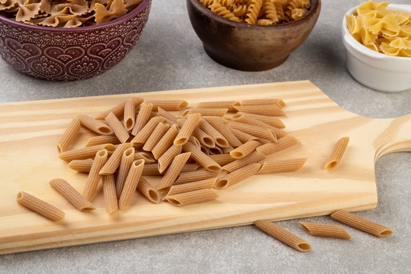assorted whole wheat pasta on bowls over wooden table - Тёплый салат из мидий
