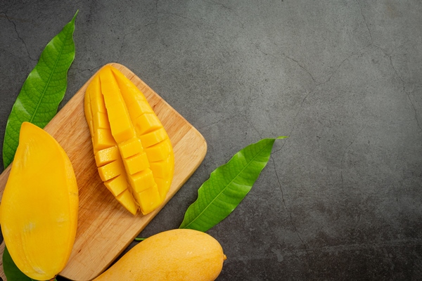 beautiful chopped ripe mango on dark wooden surface - Салат фруктовый со шпинатом и гранатом