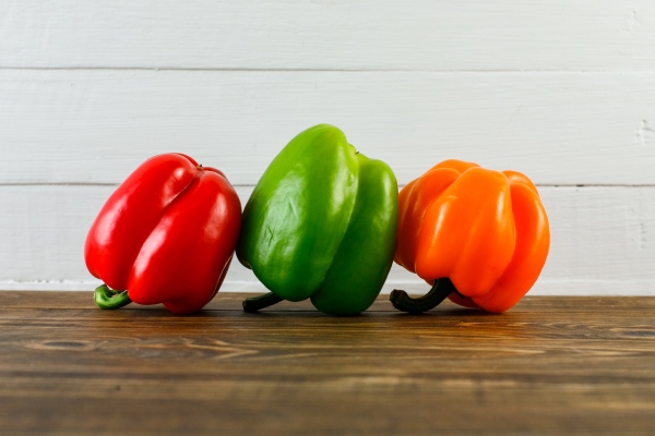 bell peppers on dark and white wooden surface side view - Рагу из красного перца с кальмаром
