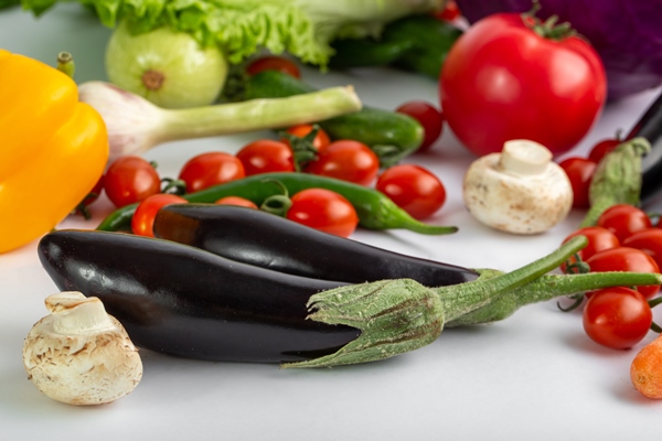 black eggplants fresh and ripe colored vegetables such as black eggplants and others on white desk - Постные баклажанные рулеты с орехами