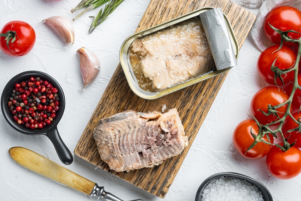 canned wild pink salmon set on wooden cutting board on white table with herbs and ingredients top view flat lay - Постный салат "Мимоза" с рыбой