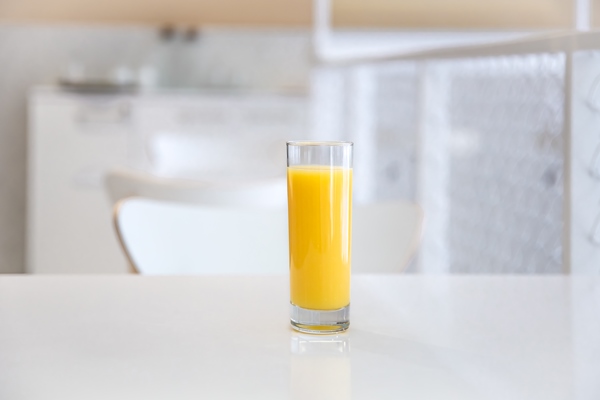 close up of a glass of orange juice on a blurred light background of a cafe interior - Постные маффины на соке
