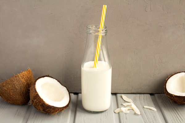 coconut milk in the glass bottle and coconuts on the grey table - Пряный рис с креветками, постный стол