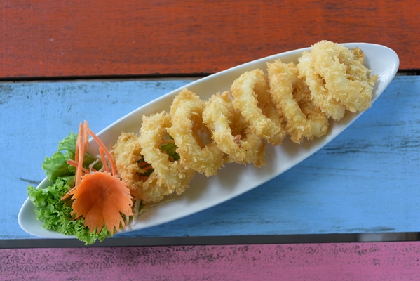 deep batter fried squid rings calamari on vintage wood table top view - Кальмары во фритюре