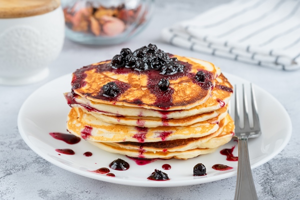 delicious small pancakes drizzled with blueberry jam on a white plate - Овсяные постные оладьи