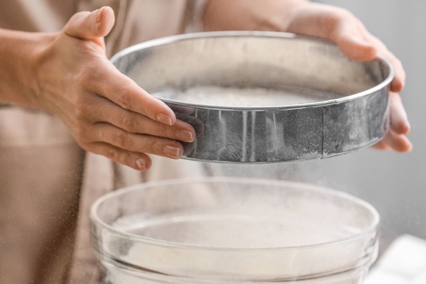 female chef sifting flour into glass bowl closeup - Постная медовая чайная коврижка
