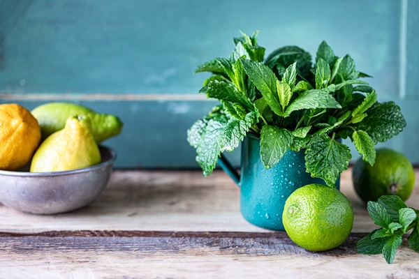 fresh organic mint and lemon balm in a metal mug and limes and lemons on a wooden table copy space - Чай с малиной