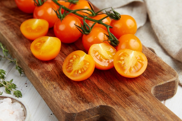 fresh yellow cherry tomatoes on white wooden background - Салат овощной с кунжутом и гранатом