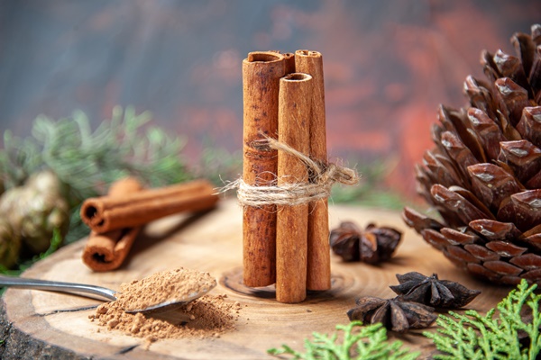 front view cinnamon sticks cinnamon powders pinecone anises on wood board on dark - Пирог "Рождественский венок"