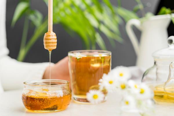 front view person holding glass with tea and honey dipper - Чай с боярышниковым цветом