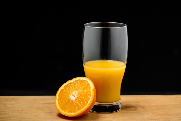 glass of juice and half orange on wooden desk - Цитрусовый мусс