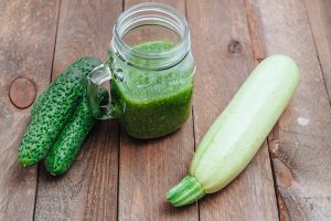 green raw smoothie in a glass mason jar and green vegetables on wooden boards cucumbers and zucchini still life - Смузи из огурца и кабачка