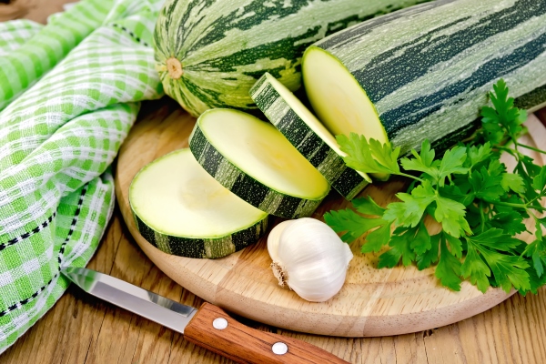 green striped zucchini garlic parsley napkin knife on background wooden board - Оладьи с нутовой мукой