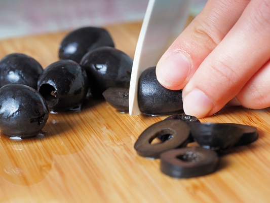 hand cutting black olives with knife - Бутерброды с тунцом и томатом