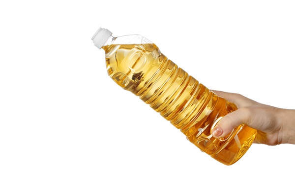 hand of woman pouring cooking oil from plastic bottle isolated on white background - Постное кокосовое печенье