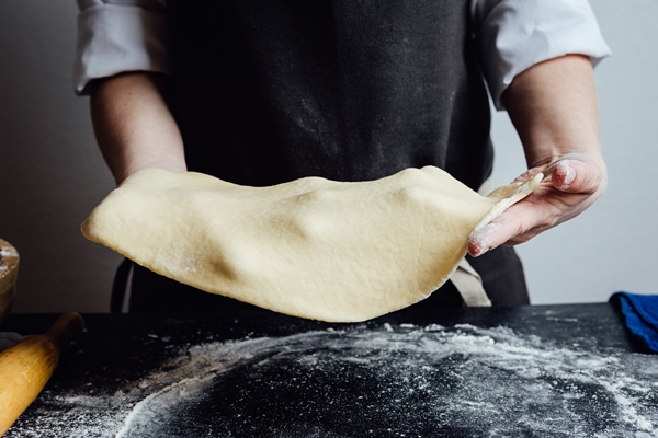 hands of cook working with rolled shortcrust dough - Пирожки из слоёного теста постные