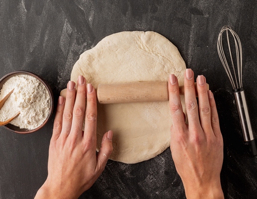 hands rolling bread dough with whisk - Пита