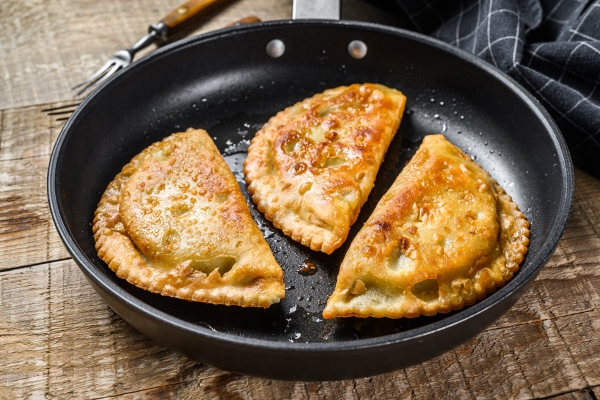 homemade fried chebureks with meat and herbs in a pan traditional caucasian cuisine - Постные чебуреки с картофелем