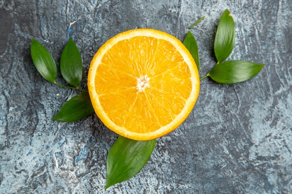 horizontal view of cut in half fresh orange with leaves on gray background stock photo - Салат из моркови с фруктами