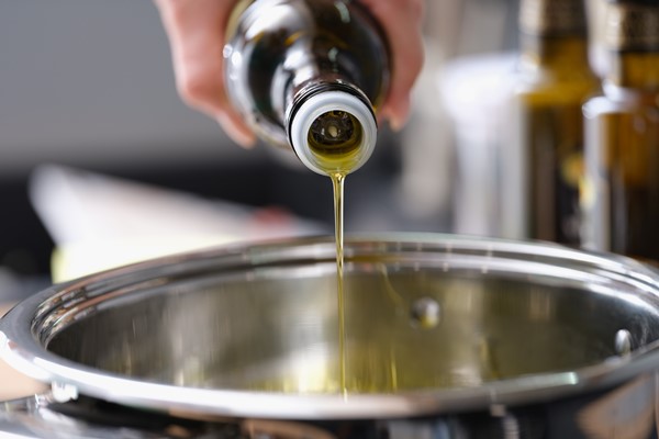 olive oil is poured from a bottle into a saucepan - Постный кекс с черносливом