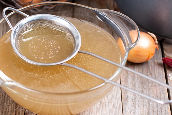 passing the bone broth through a sieve concentrated bone broth in a bowl on the table - Грибное сациви