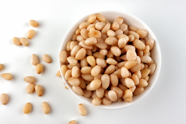 pine nuts in a ceramic bowl on a white background top view - Постные макароны с креветками и чесноком