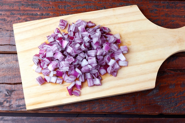 portion of chopped raw red onions over rustic wooden table close up view - Постные капустные оладьи