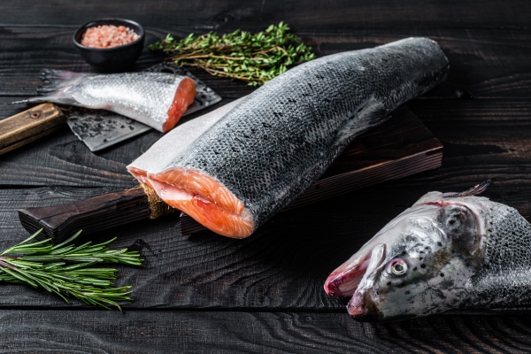 raw cut salmon fish on a wooden cutting board with chef cleaver black wooden background top view - Сёмга, запечённая с луком и картофелем, постный стол