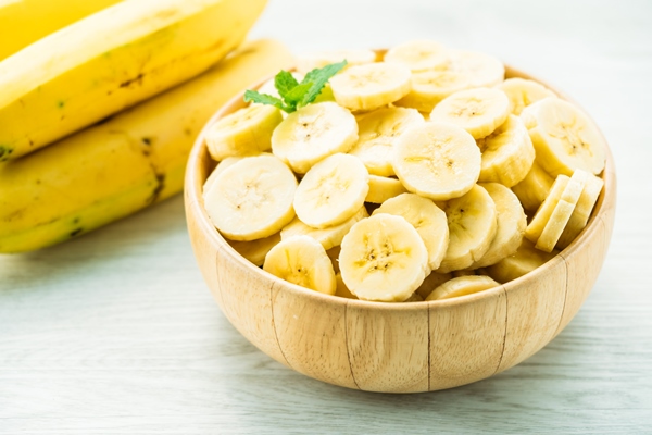 raw yellow banana slices wooden bowl - Постные оладьи из кокоса и банана