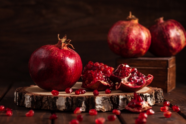 red ripe pomegranates on a wooden background the cut fruits of the pomegranate tree - Постный салат с мандаринами