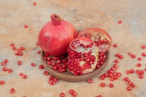 ripe pomegranates and seeds on wooden plate - Гранатовый напиток