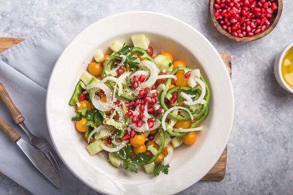 salad with cucumber tomato cherry pomergranate onion and paprika on grey concrete surface 1 - Салат овощной с кунжутом и гранатом