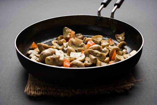 sauteed mushroom or fried toadstool in a frying pan over moody background selective focus - Постный салат из грибов с картофелем