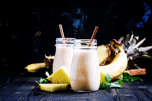 smoothies from pineapple and banana in glass bottles dark background selective focus - Ананасово-кокосовый смузи