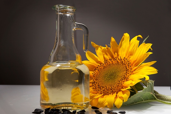 sunflower oil in a transparent jug with sunflower flower - Перловая каша с постным маслом