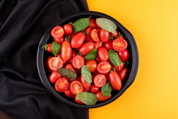 the fresh red bright cherry tomatoes in metal pan on black cloth on a yellow surface - Салат из рукколы и креветок