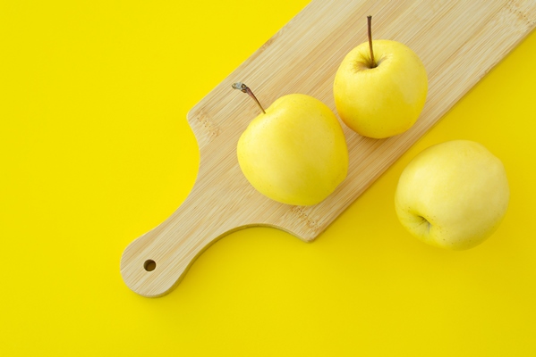 three yellow apples on a wooden chopping board on yellow background fresh ripe juicy yellow fruits - Салат с консервированным кальмаром