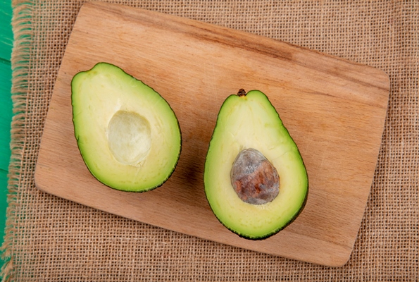 top view of healthy and fresh halved avocado on a wooden kitchen board on sack cloth surface - Салат "Лодочки" из авокадо