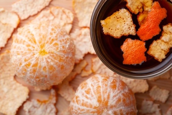 two peeled tangerines near cup of hot tea with some added peel adding tangerine peel to tea - Мандариновый чай