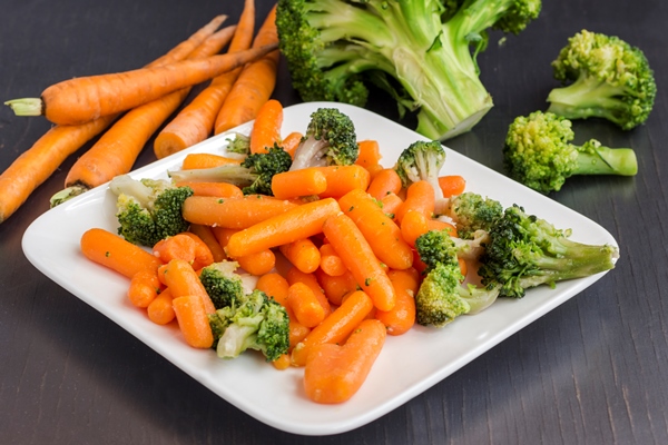 vegetable salad broccoli and carrots in a white plate on black - Варёная морковь